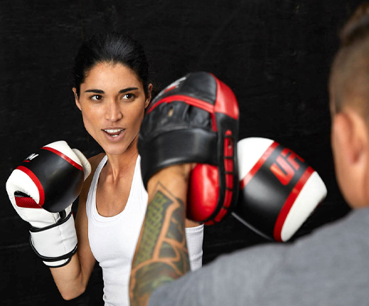 photo of woman in white shirt boxing with man in gray shirt