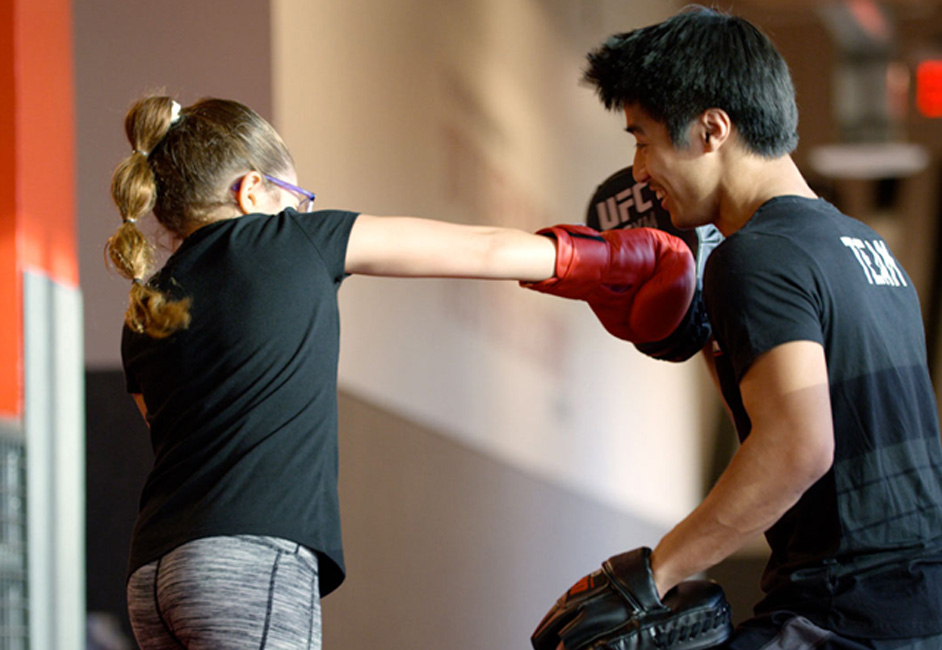 photo of female child boxing with male trainer in black shirt