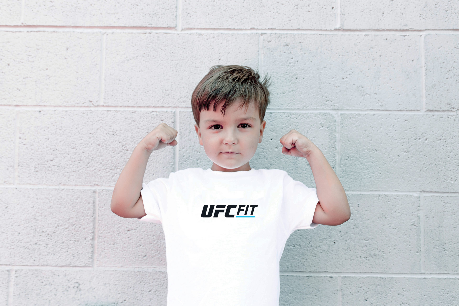 photo of male child in white UFC Fit shirt posing with arms flexed