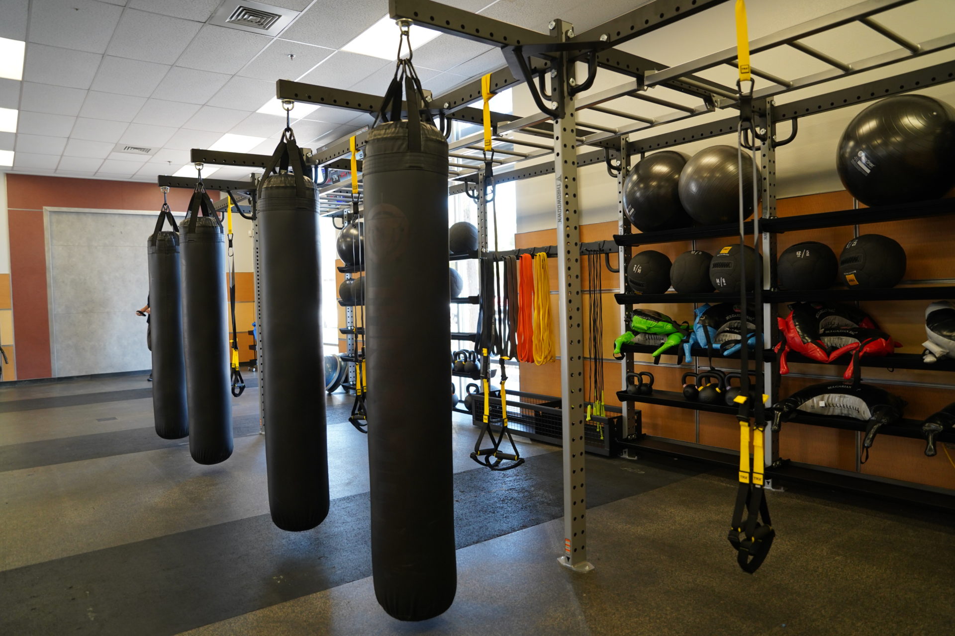 photo of a row of punching bags and workout gear on racks