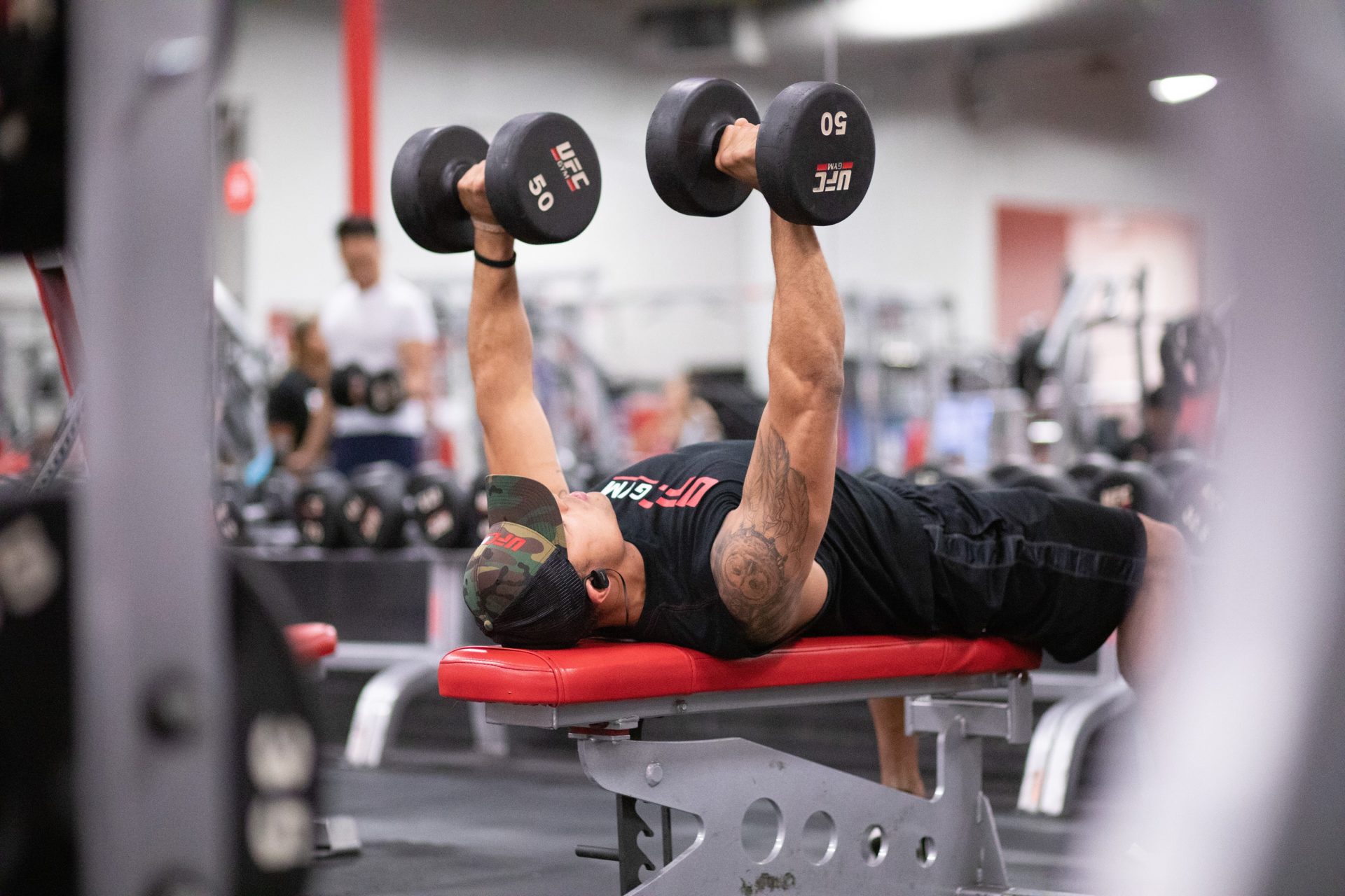 photo of man in black shirt lifting black weights on workout bench