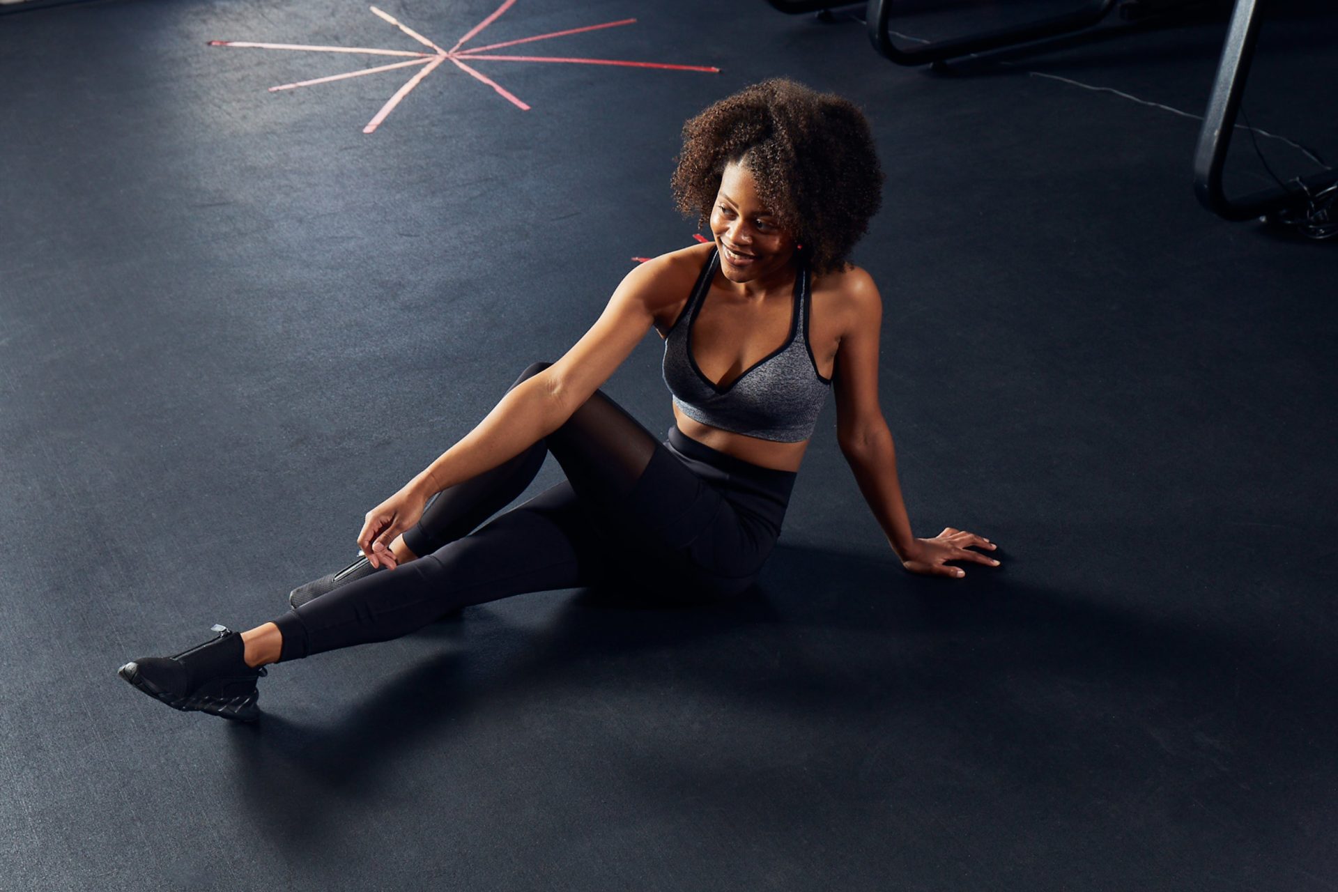 photo of woman in black workout clothing smiling and stretching
