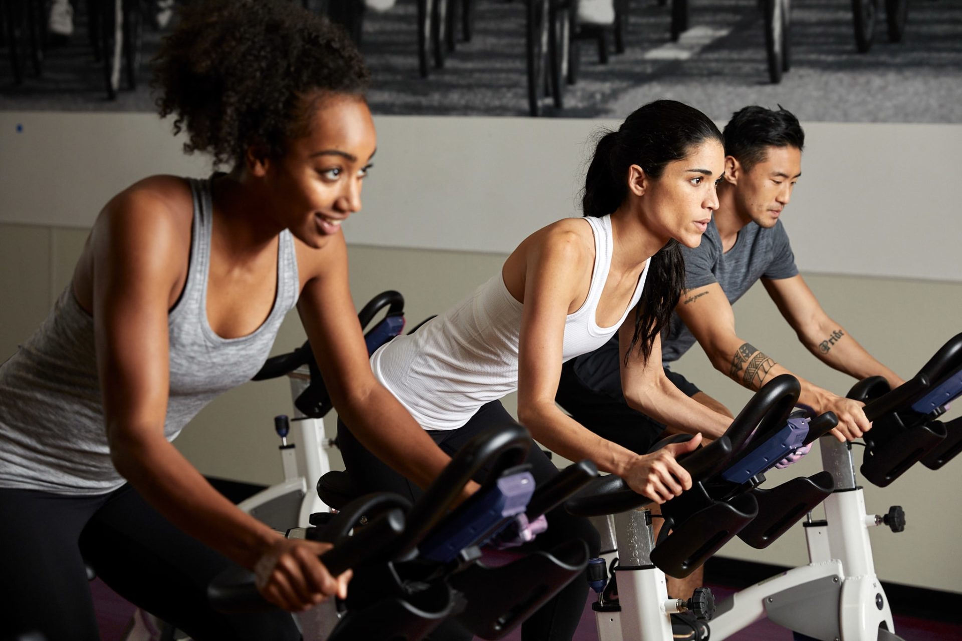 photo of two women and one man using exercise bikes