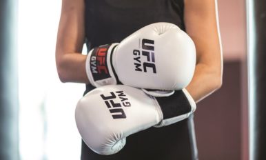 Image of woman’s torso with white UFC GYM boxing gloves on her hands
