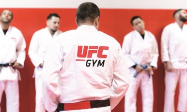 Image of a man in white UFC GYM uniform facing a group of similarly dressed men