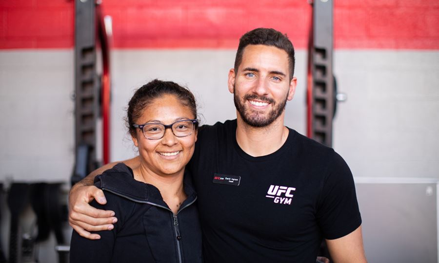 Image of smiling man in UFC GYM shirt with arm around smiling woman in black shirt