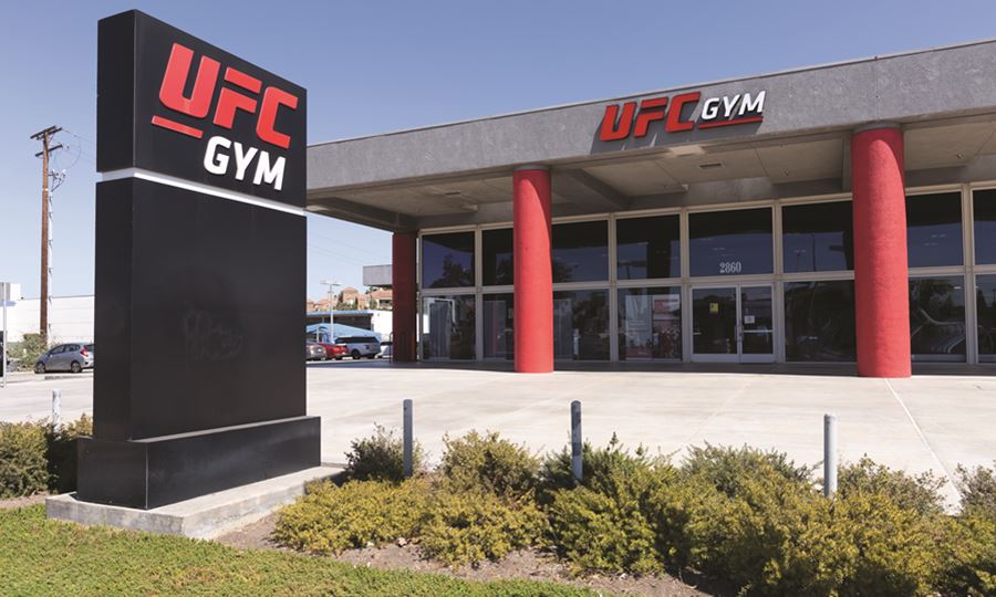 Image of gray and red exterior UFC GYM location with black sign