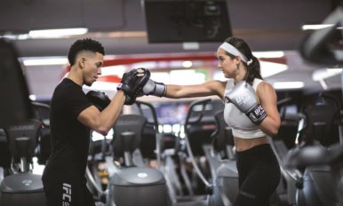 A female member punches a male coache’s hand during boxing training.
