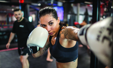 Image of a woman with white gloves boxing in a UFC GYM