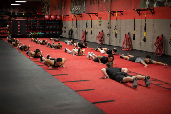group of people working out on a red and black carpet at a ufc gym franchise
